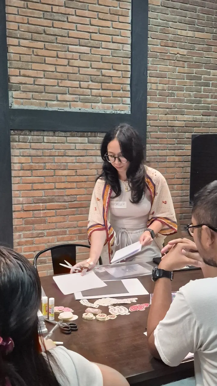 Fasilitator memandu peserta dengan materi dan alat aktivitas refleksi di atas meja.