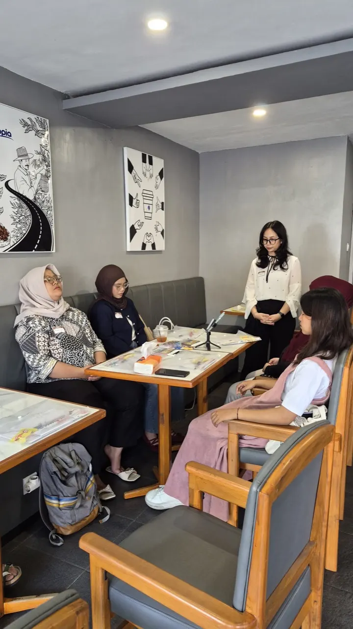 Fasilitator memandu sesi refleksi tenang dengan peserta yang duduk melingkar di ruang kecil.